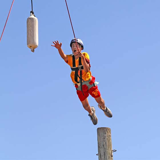 cadete de campamento de verano saltando fuera del polo de poder del curso de cuerdas